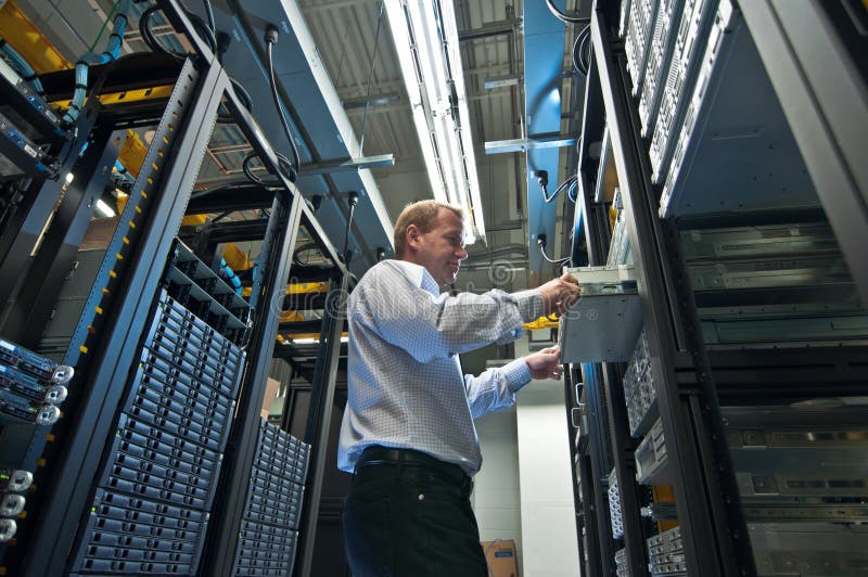 IT administrator installing a new rack mount server. Large scale storage server is also seen. IT administrator installing a new rack mount server. Large scale storage server is also seen.