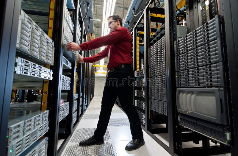 IT administrator installing a new rack mount server. Large scale storage server is also seen. IT administrator installing a new rack mount server. Large scale storage server is also seen.