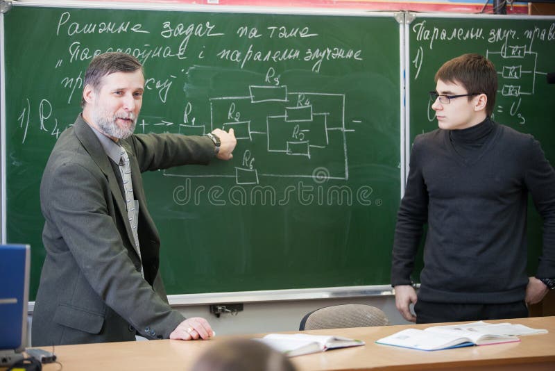 Experienced teacher giving comments on teenage boy work stock images Experienced teacher giving comments on teenage boy work stock images