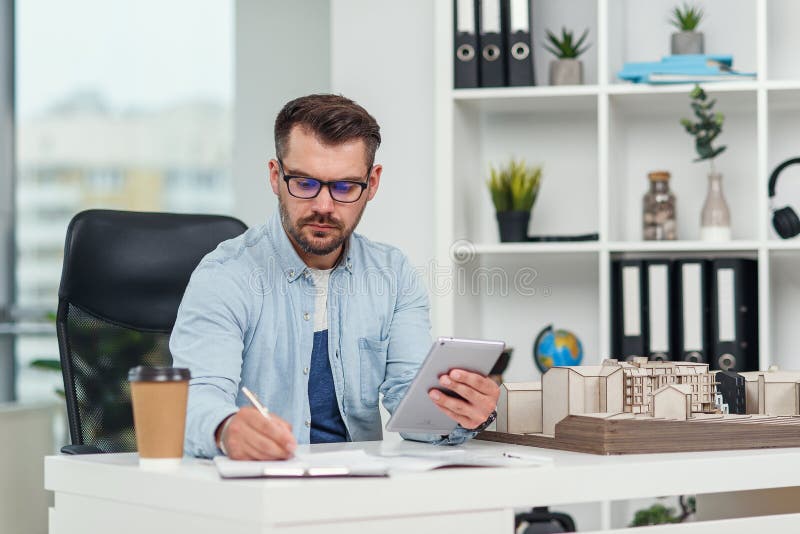 Experimentados arquitectos masculinos en la oficina inspeccionan el proyecto de complejo residencial y realizan cálculos usando un imagen de archivo