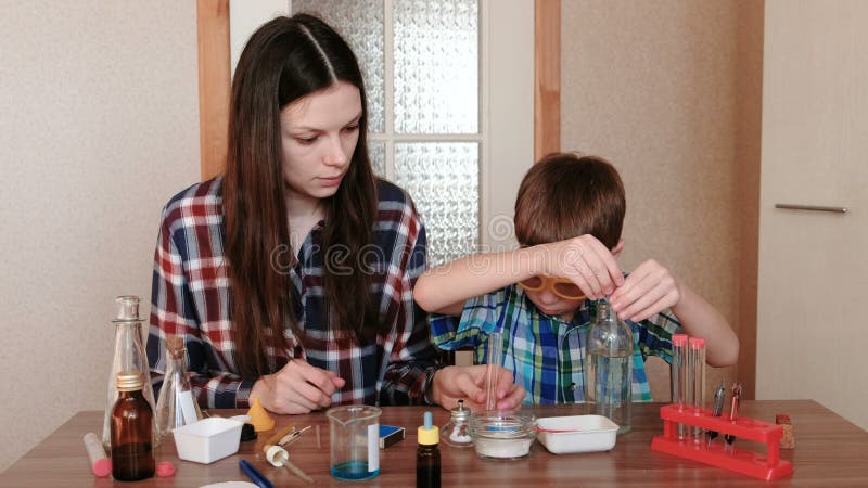 Experiências na química em casa A mãe e o filho fazem uma experiência da ciência junto