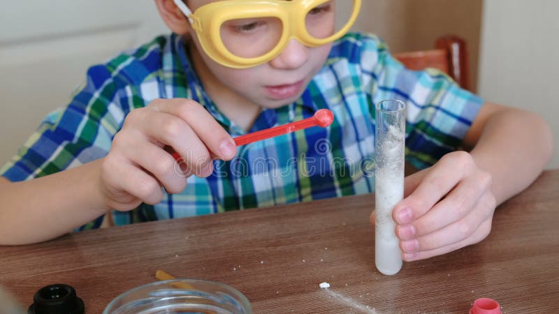 Experiências na química em casa Reação química com a liberação do gás no tubo de ensaio no menino, mãos de s