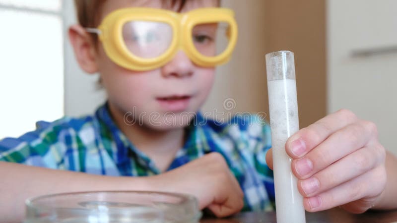 Experiências na química em casa Reação química com a liberação do gás no tubo de ensaio no menino, mãos de s