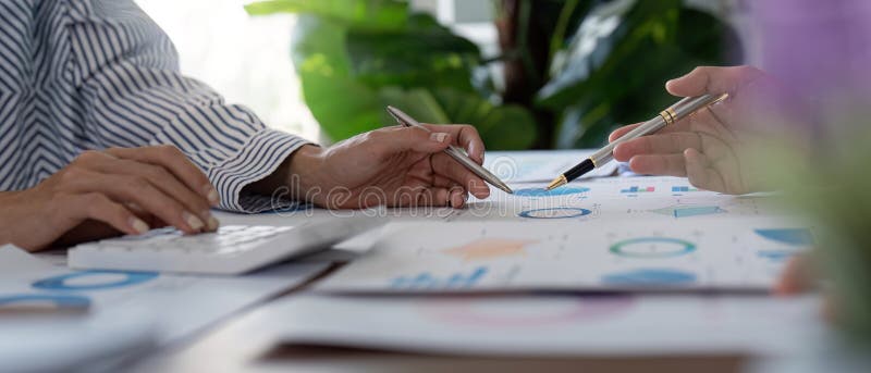 Experts financiers travaillant ensemble sur les données financières et les calculs dans un bureau brillant. Les experts financiers collaborent sur des données et des calculs financiers mettant l'accent sur le travail d'équipe et les compétences analytiques dans un environnement de bureau brillant.