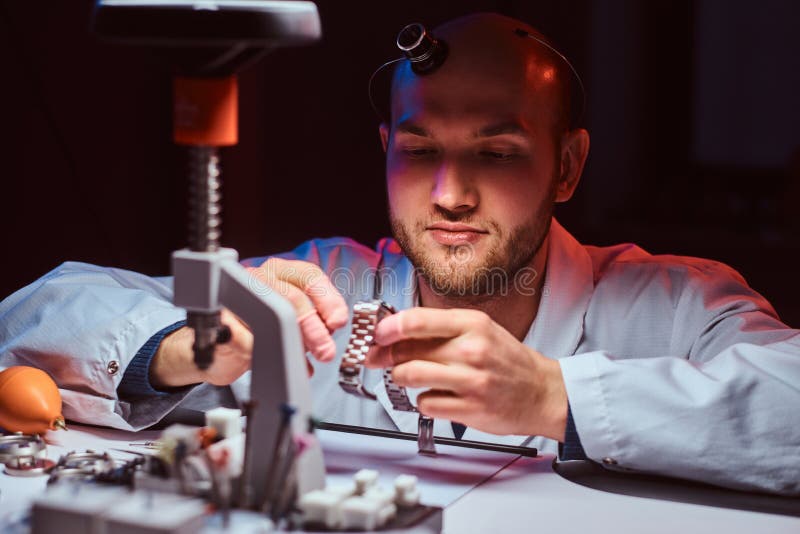 Expirienced-Uhrmacher tut Stich f?r die Uhr der custmers an seiner Werkstatt stockbild Expirienced-Uhrmacher tut Stich f?r die Uhr der custmers an seiner Werkstatt stockbild