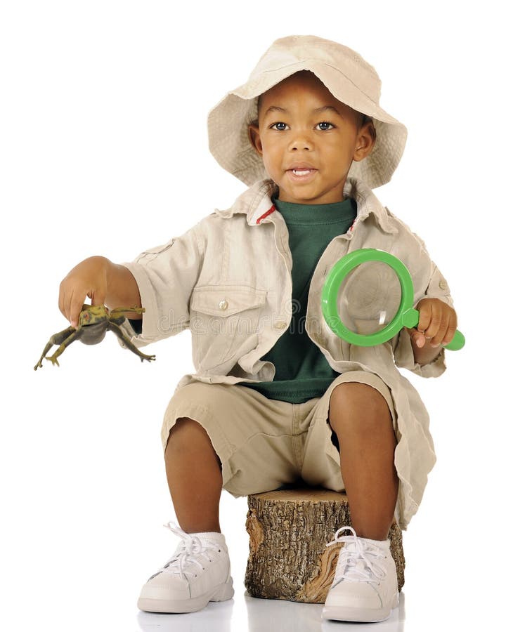 An adorable preschooler sitting on a tree stump in safari attire. He's hopping a frog in one hand (with motion blur) and holding a magnifying glass in the other. An adorable preschooler sitting on a tree stump in safari attire. He's hopping a frog in one hand (with motion blur) and holding a magnifying glass in the other.