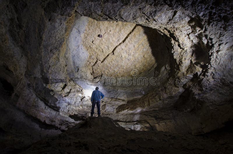 Explorador do homem na caverna enorme subterrânea