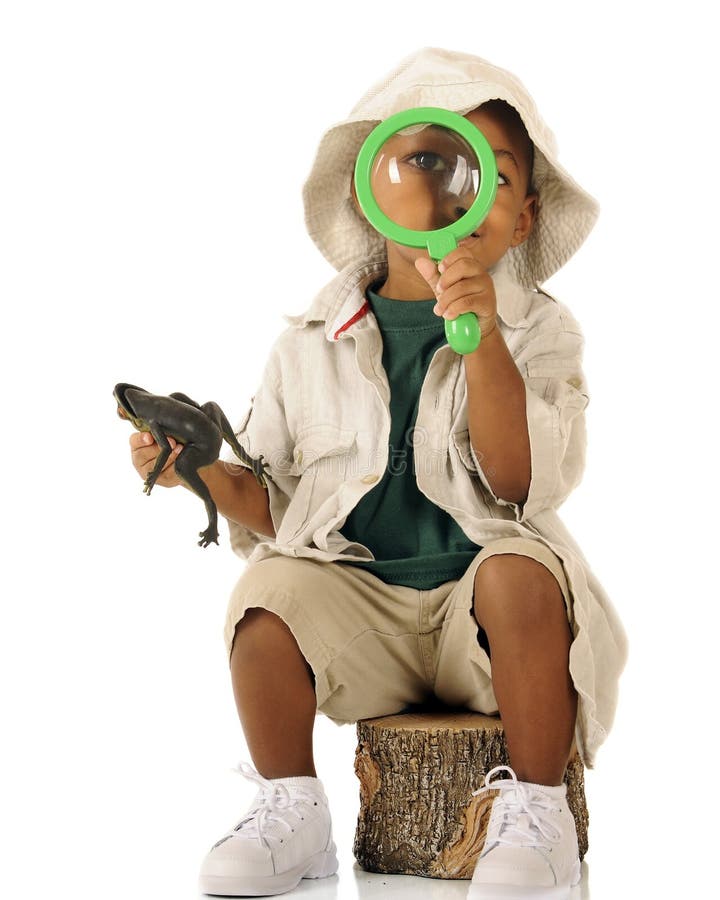 An adorable preschooler looking at the viewer through a magnifying glass. He's dressed in beiige safari clothes and holds a frog in his other hand. An adorable preschooler looking at the viewer through a magnifying glass. He's dressed in beiige safari clothes and holds a frog in his other hand.