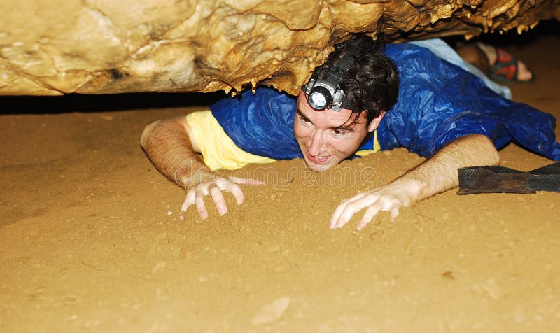 Man exploring a cave through a narrow passage. Man exploring a cave through a narrow passage