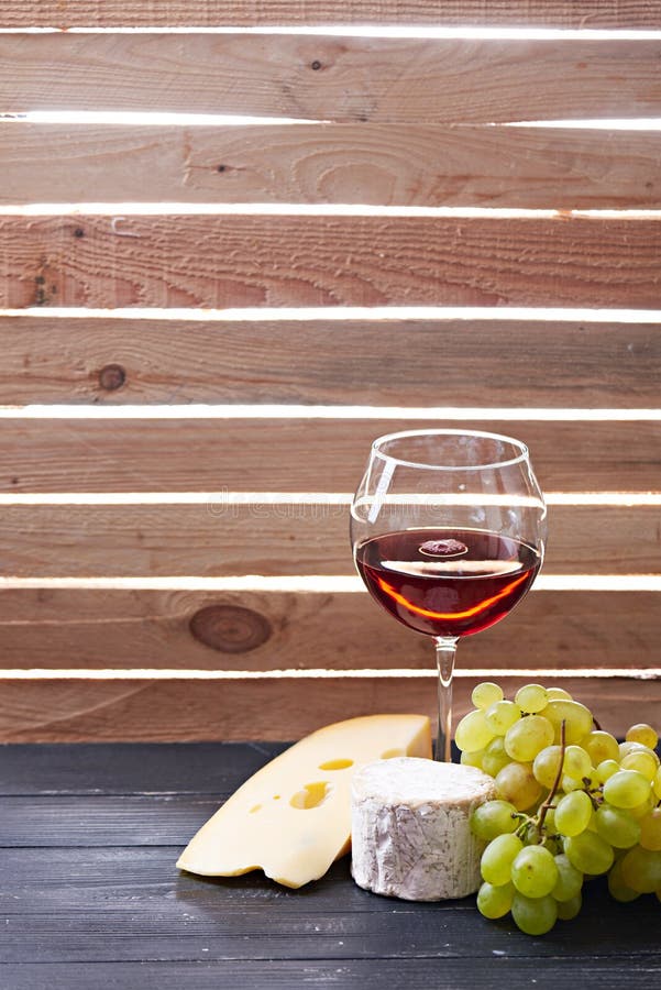 Exponeringsglas av rött vin som tjänas som med druvor och ost arkivfoton Exponeringsglas av rött vin som tjänas som med druvor och ost arkivfoton