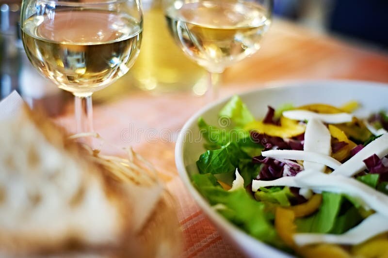 Exponeringsglas av vitt vin och sallad på tabellkafét arkivbilder Exponeringsglas av vitt vin och sallad på tabellkafét arkivbilder