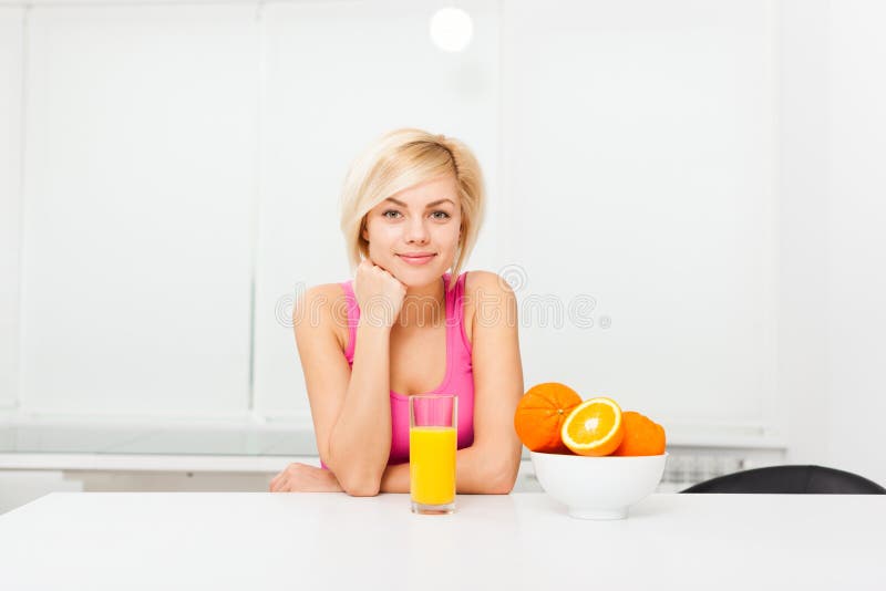 Exponeringsglas för drink för orange fruktsaft för kvinna i hennes kök