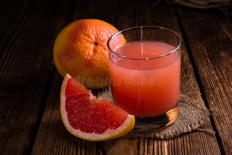 Glass with Grapefruit Juice (close-up shot) on wooden background. Glass with Grapefruit Juice (close-up shot) on wooden background