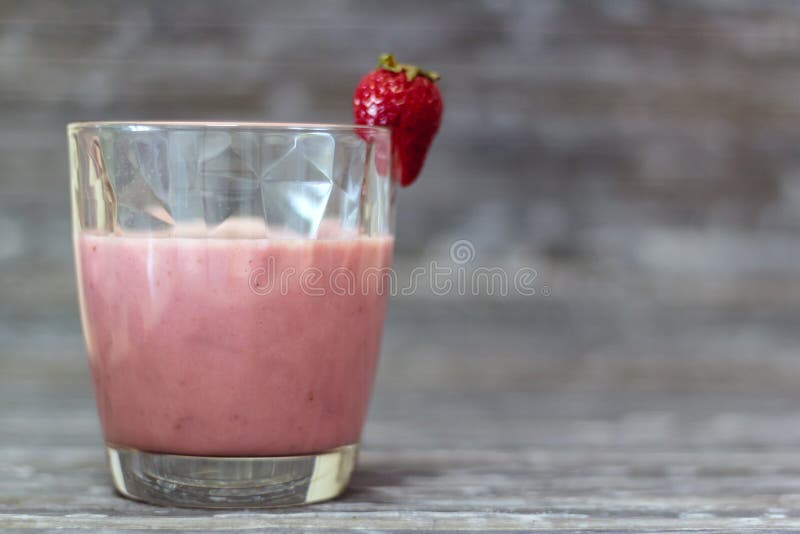 Exponeringsglas med naturlig jordgubbemilkshake p? lantlig bakgrund royaltyfri bild Exponeringsglas med naturlig jordgubbemilkshake p? lantlig bakgrund royaltyfri bild
