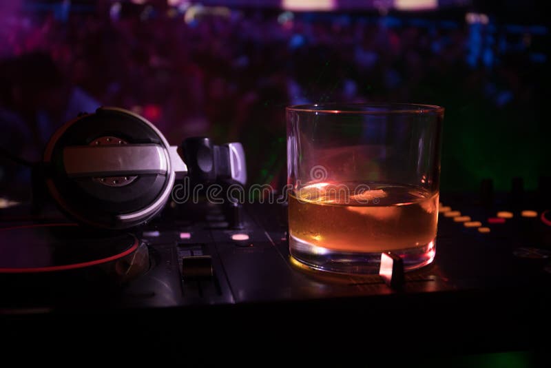 Exponeringsglas med whisky med iskuben inom på dj-kontrollant på nattklubben Dj-konsol med klubbadrinken på musikpartiet i nattkl royaltyfri foto Exponeringsglas med whisky med iskuben inom på dj-kontrollant på nattklubben Dj-konsol med klubbadrinken på musikpartiet i nattkl royaltyfri foto