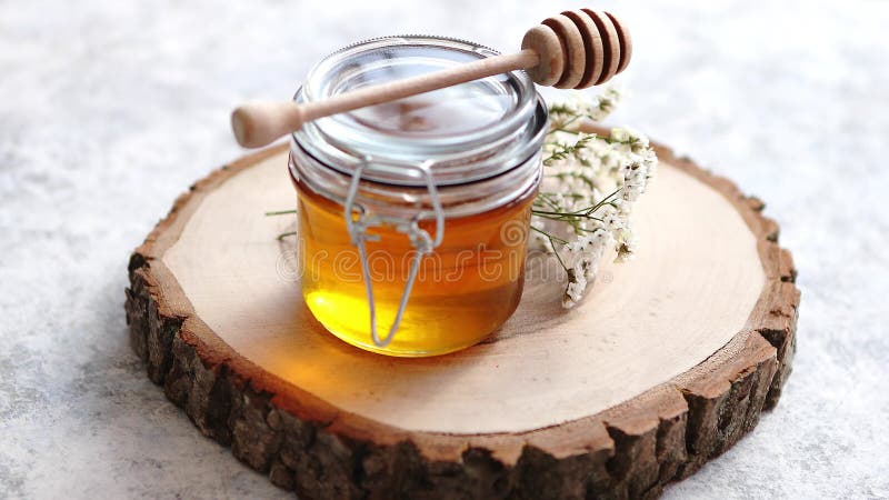 Exponeringsglaskrus mycket av ny honung som förläggas på skiva av trä