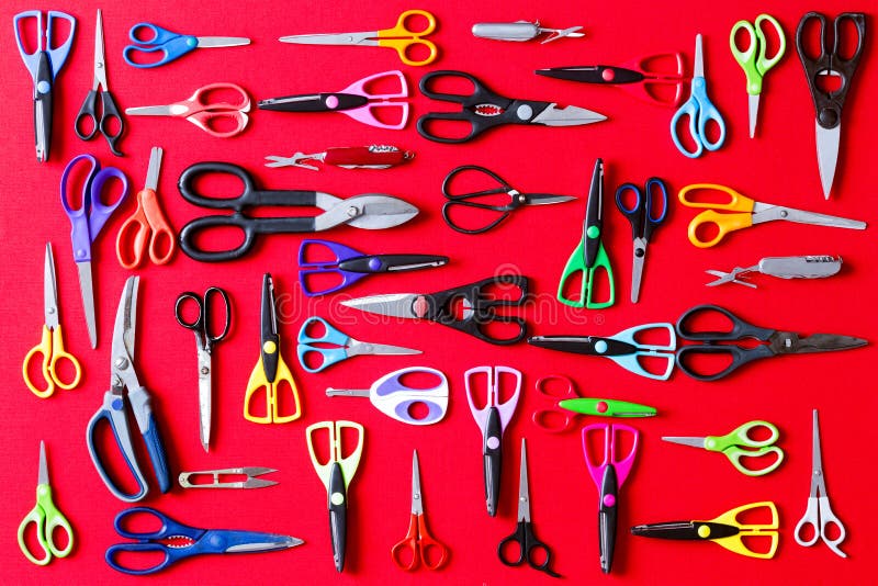 Display of multiple different pairs of domestic scissors on red conceptual of scissors for everyone and for every different task, overhead view. Display of multiple different pairs of domestic scissors on red conceptual of scissors for everyone and for every different task, overhead view