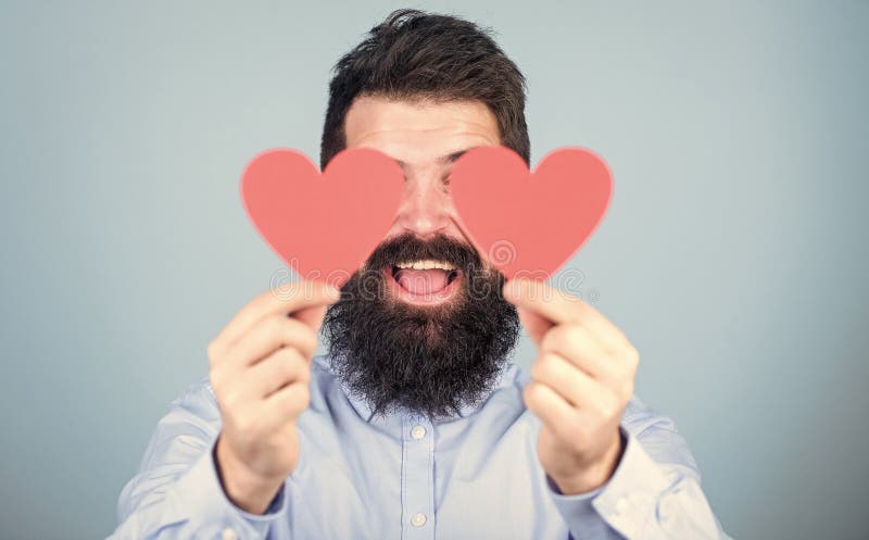 Expressing his love. Sexy valentine man covering eyes with love cards. Hipster with small hearts. Bearded man holding royalty free stock photos