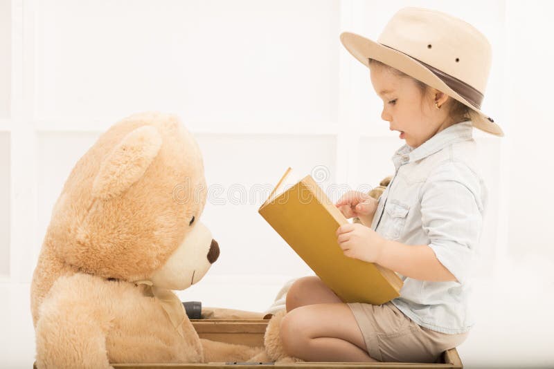 Expressive little girl reading to her teddy bear