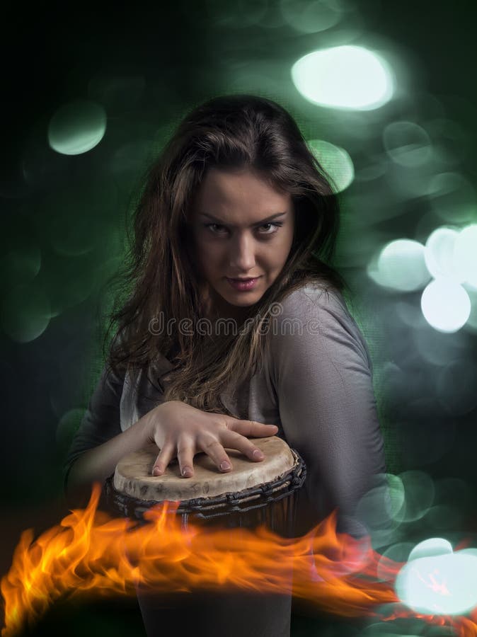 Ritratto di bella emotivo, capelli lunghi bruna giocando djembe drum, su isolato alleggerito sfondo verde e il fuoco in primo piano.