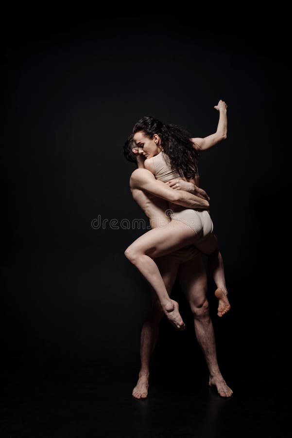 Expressive young performers dancing against black background stock photos