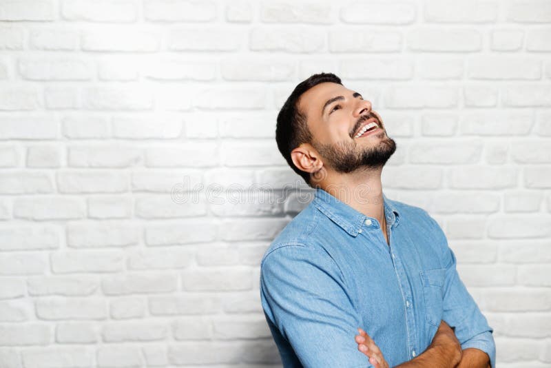 Expressões faciais do homem novo da barba na parede de tijolo fotografia de stock Expressões faciais do homem novo da barba na parede de tijolo fotografia de stock