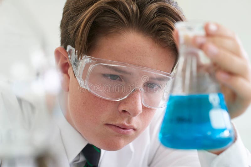Expérience de conduite de chimie d'élève masculin dans la classe de la Science image stock Expérience de conduite de chimie d'élève masculin dans la classe de la Science image stock