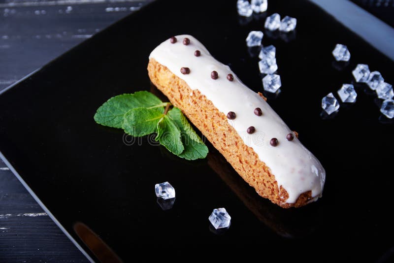 Exquisite Cream Dessert Eclair with Fresh Mint Leaves Stock Photo