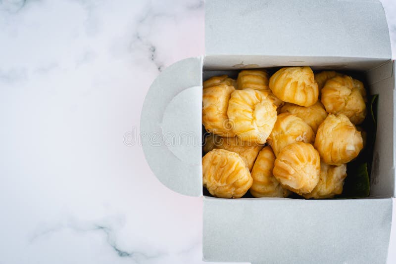Exquisito eclair vainilla crema choux dough relleno con una panadería casera crema en embalaje de caja de papel fotografía de archivo