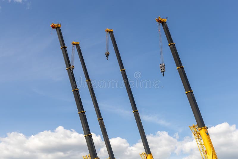 Extended booms of four mobile cranes with hook. Construction and repair equipment for lifting loads