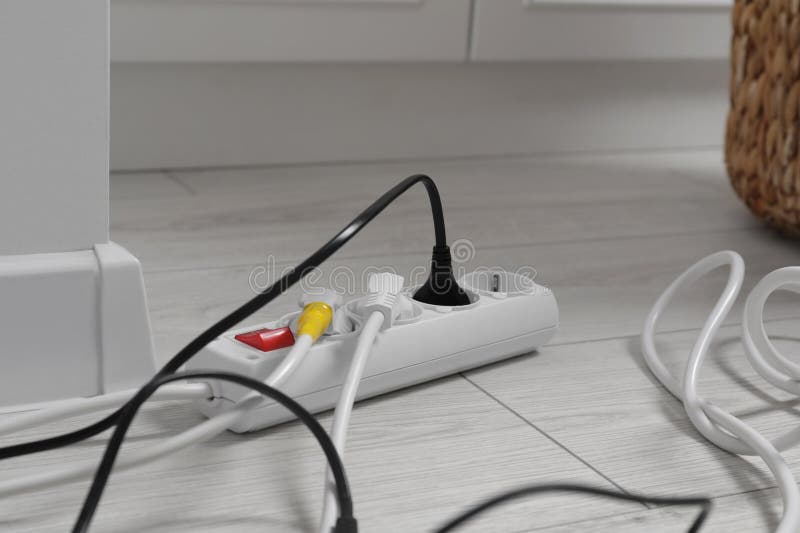Extension cord with electrical plugs on white floor indoors, closeup. Damaged extension cord stock images, royalty-free photos and pictures