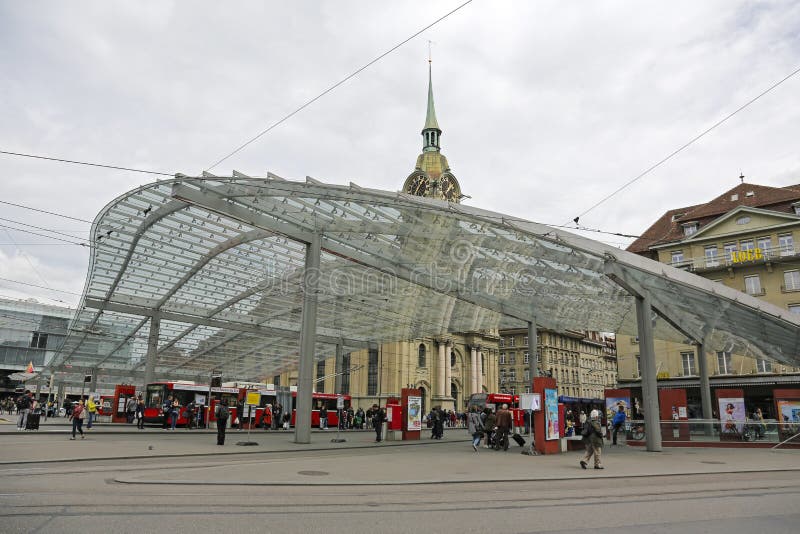 Bern, Switzerland - April 17, 2017: On the extensive tram and bus stop in the city center many people in the distance can be seen. It is a modern public transport stop which is covered by a glass roof. Bern, Switzerland - April 17, 2017: On the extensive tram and bus stop in the city center many people in the distance can be seen. It is a modern public transport stop which is covered by a glass roof