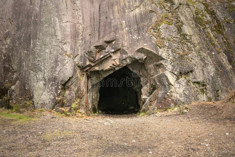 Exterior of the cave on Norway coast. Stone wall with dark entrance to cave. Exterior of the cave on Norway coast. Stone wall with dark entrance to cave.