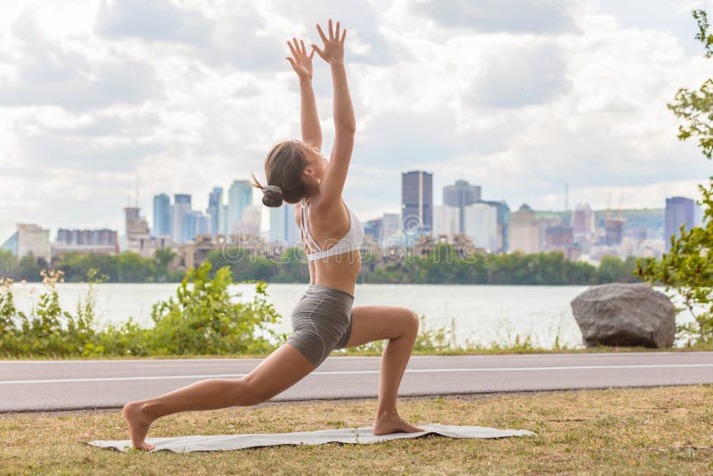 Exterior de la clase de la salud de la yoga en la mujer del parque de la ciudad que hace actitud creciente de la alta estocada en fotografía de archivo libre de regalías Exterior de la clase de la salud de la yoga en la mujer del parque de la ciudad que hace actitud creciente de la alta estocada en fotografía de archivo libre de regalías
