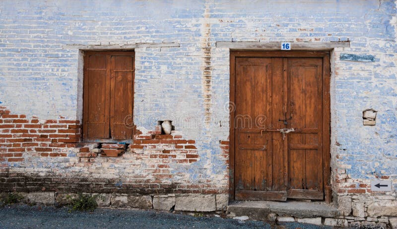 Exterior of an old village house with blue stoned wall and closed vitnage door and window. Exterior of an old village house with blue stoned wall and closed vitnage door and window.