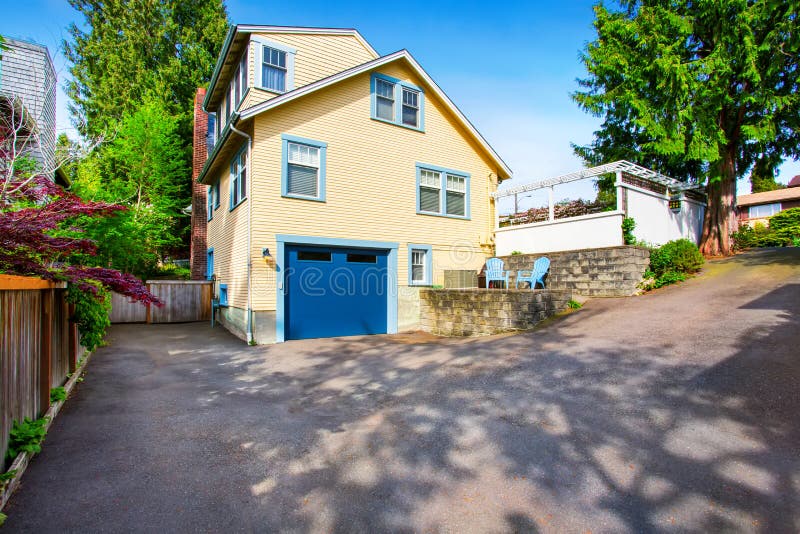 Exterior of yellow house with blue garage door and asphalt driveway