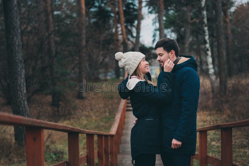 Exteriores felizes dos pares novos loving junto em acolhedor aquecem a caminhada na floresta imagens de stock Exteriores felizes dos pares novos loving junto em acolhedor aquecem a caminhada na floresta imagens de stock