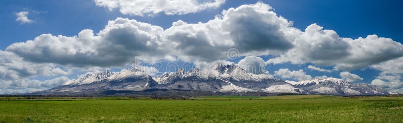Extra široké panorama hlavního hřebene vysokých tater během dubna se zasněženými kopci a modrou oblohou s mraky, vysoké tatry