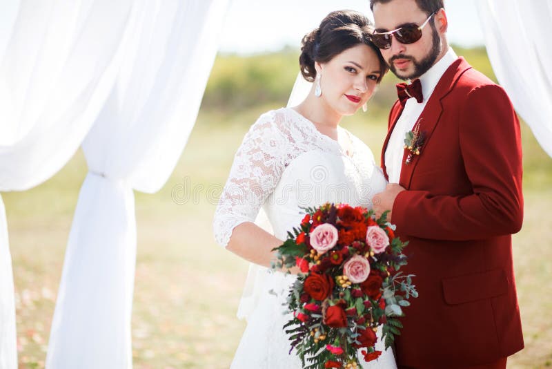Extravagante bruid en bruidegom, mooi paar, de spruit van de huwelijksfoto Mens in rood kostuum, zonnebril met vlinderdas Zonnige stock foto Extravagante bruid en bruidegom, mooi paar, de spruit van de huwelijksfoto Mens in rood kostuum, zonnebril met vlinderdas Zonnige stock foto