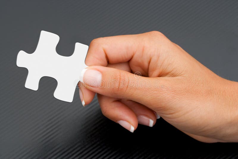 Extreme Close up of female hand holding white puzzle piece. Extreme Close up of female hand holding white puzzle piece.