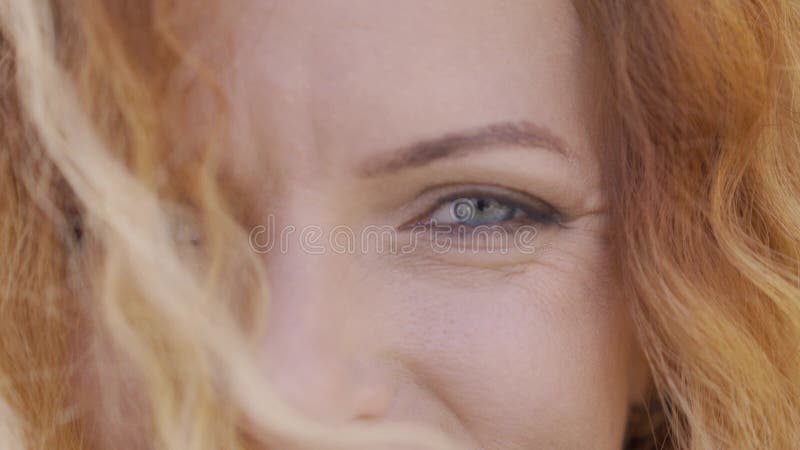 Extrema cara de mujer madura de cabello rojo con cabello rizado sonriendo alegremente mirando la cámara. Belleza natural metrajes