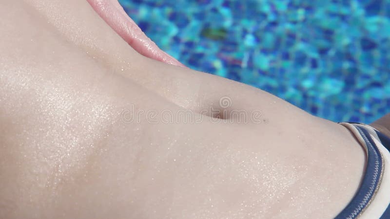 Extreme closeup of female hands applying suncream, rubbing belly