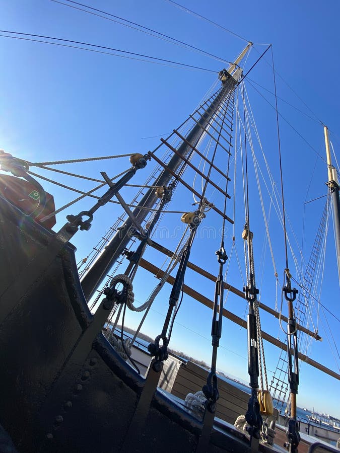 Sailing boat mast's  extreme upshot of the shroud and pulley blocks against a blue winter sky. Sailing boat mast's  extreme upshot of the shroud and pulley blocks against a blue winter sky