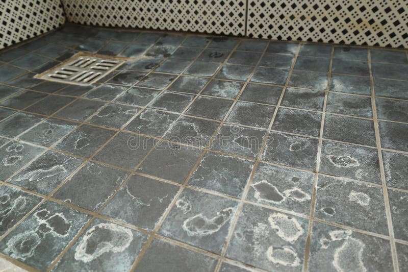 Extremely dirty bath drain mesh, hole and tiles surface covered with limescale. Marks on tiles in a shower from the water and royalty free stock photo
