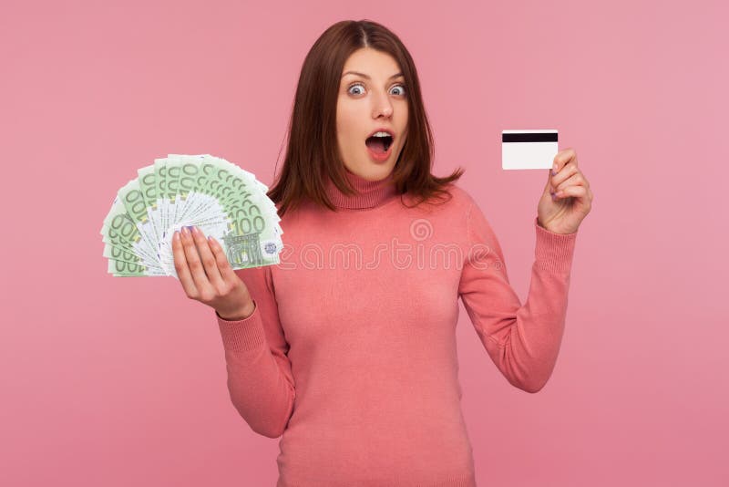 Extremely Surprised Brunette Woman Holding And Showing Credit Card And Fan Of Euro Banknotes