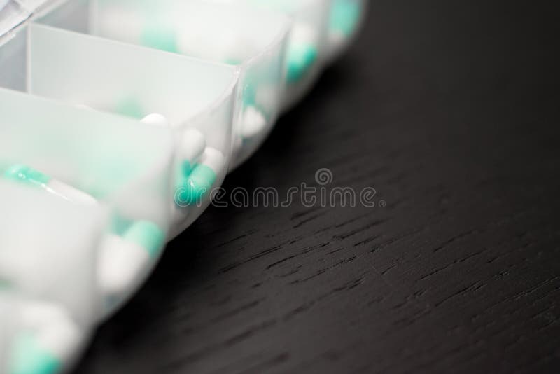 Extremo cercano para arriba de la caja de siete días de la píldora con las píldoras Fortín azul imágenes de archivo libres de regalías Extremo cercano para arriba de la caja de siete días de la píldora con las píldoras Fortín azul imágenes de archivo libres de regalías