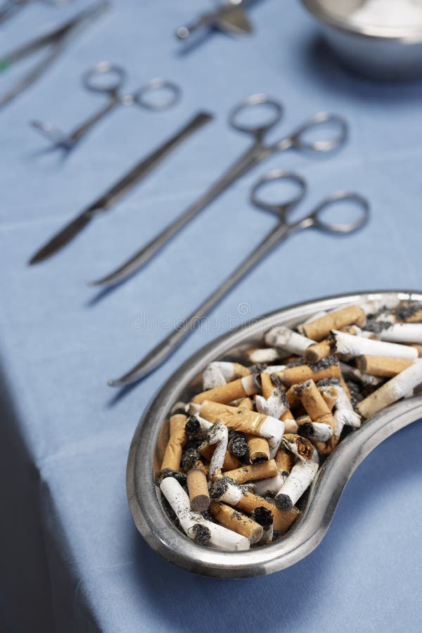 Cigarettes butts in medical tray with operating equipments on table. Cigarettes butts in medical tray with operating equipments on table