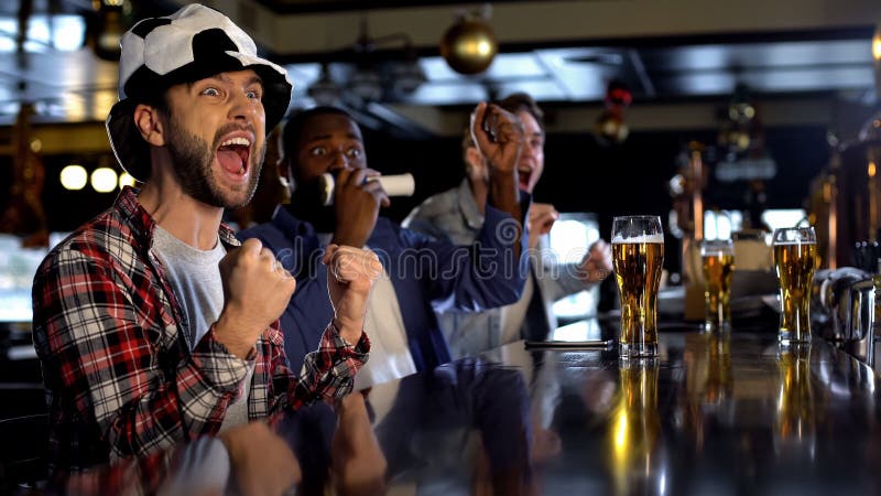 Extremt lyckliga fotbollfans som håller ögonen på leken i baren som firar göra poäng mål arkivbild Extremt lyckliga fotbollfans som håller ögonen på leken i baren som firar göra poäng mål arkivbild