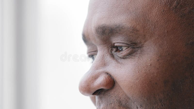 Extrême visage gros plan mature africain moyen âge homme 50s yeux mâles avec des rides regardant à distance par la fenêtre clips vidéos