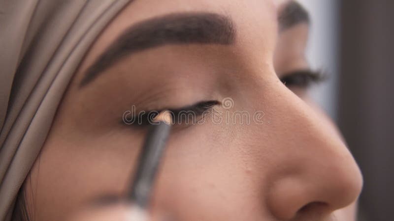 Extrêmement étroit vers le haut de la vue d'une jeune femme musulmane faisant une flèche sur sa paupière utilisant l'eyepencil no banque de vidéos